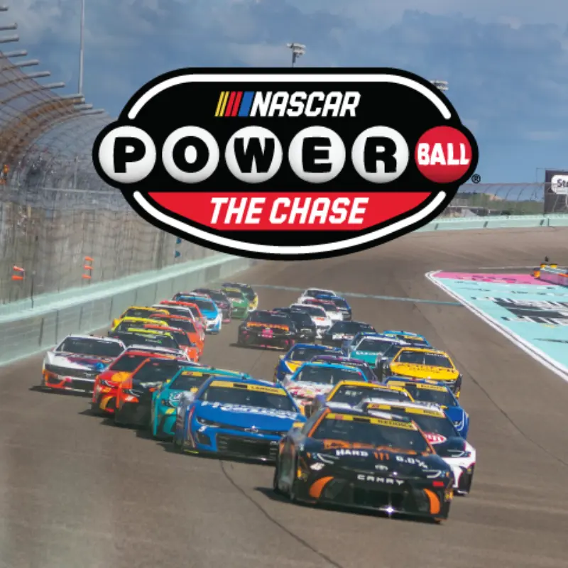NASCAR race cars speed down a track under the NASCAR Powerball The Chase logo, with grandstands and partly cloudy skies.