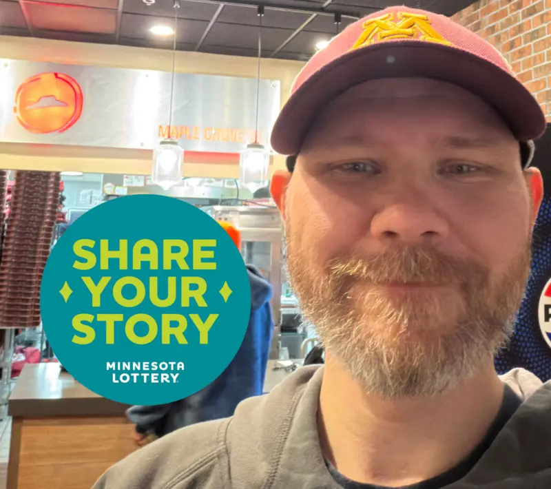 Smiling man in a maroon University of Minnesota hat at a restaurant, next to a blue and yellow "Share Your Story Minnesota Lottery" graphic.